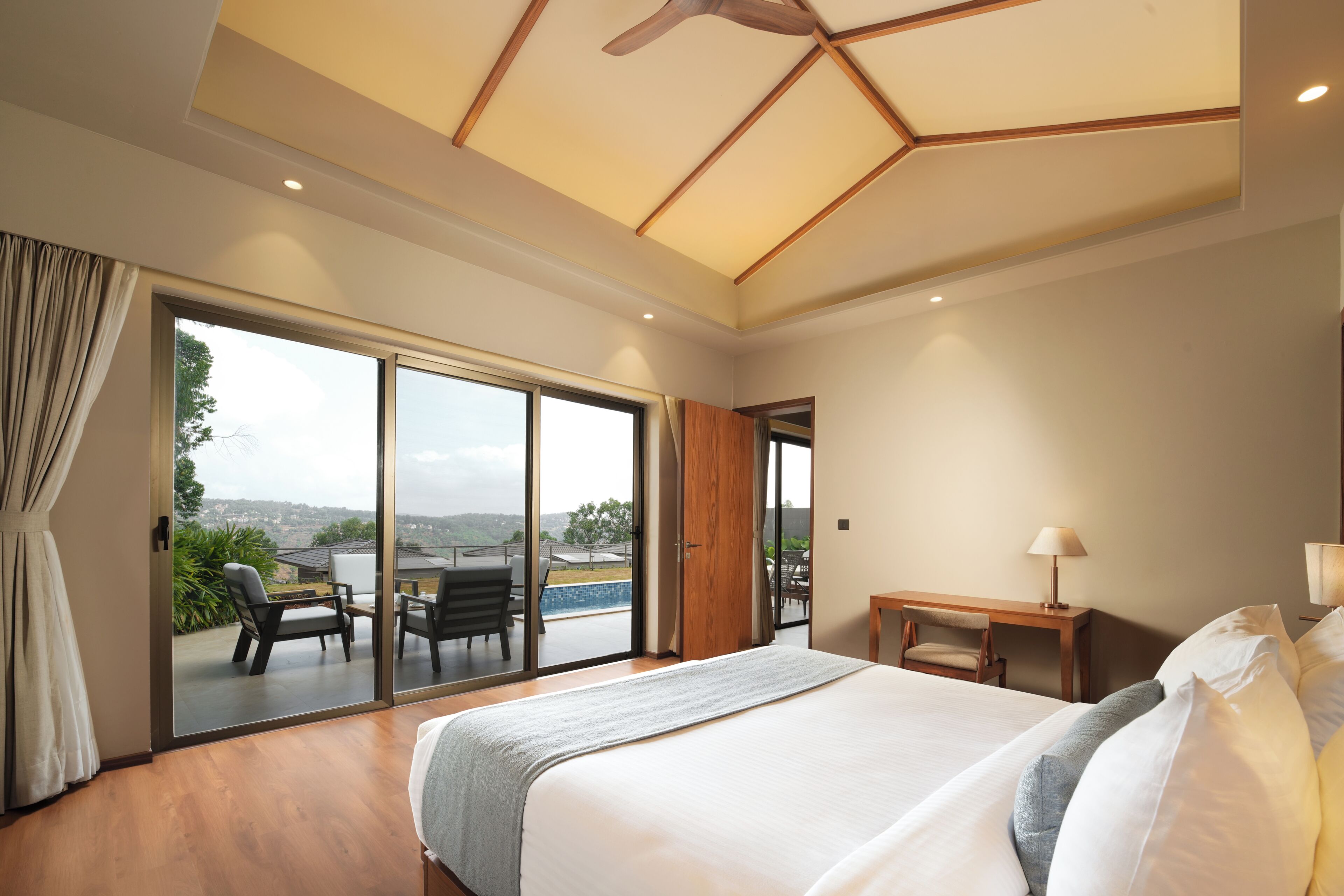 A hotel room with a large bed, a desk, and a view of the outdoors.