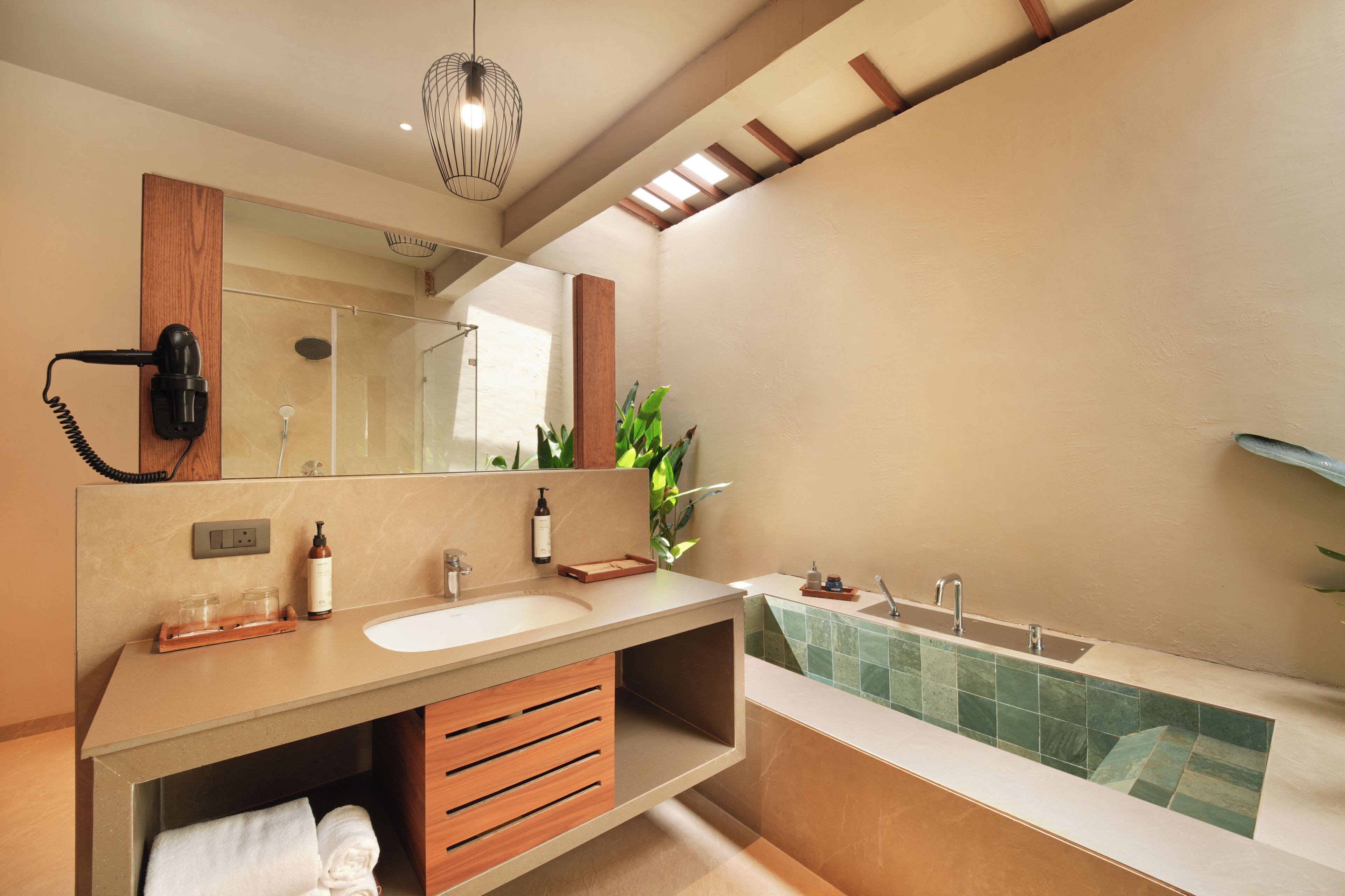 Une salle de bain moderne avec un grand miroir, deux lavabos, un sèche-cheveux et une baignoire.