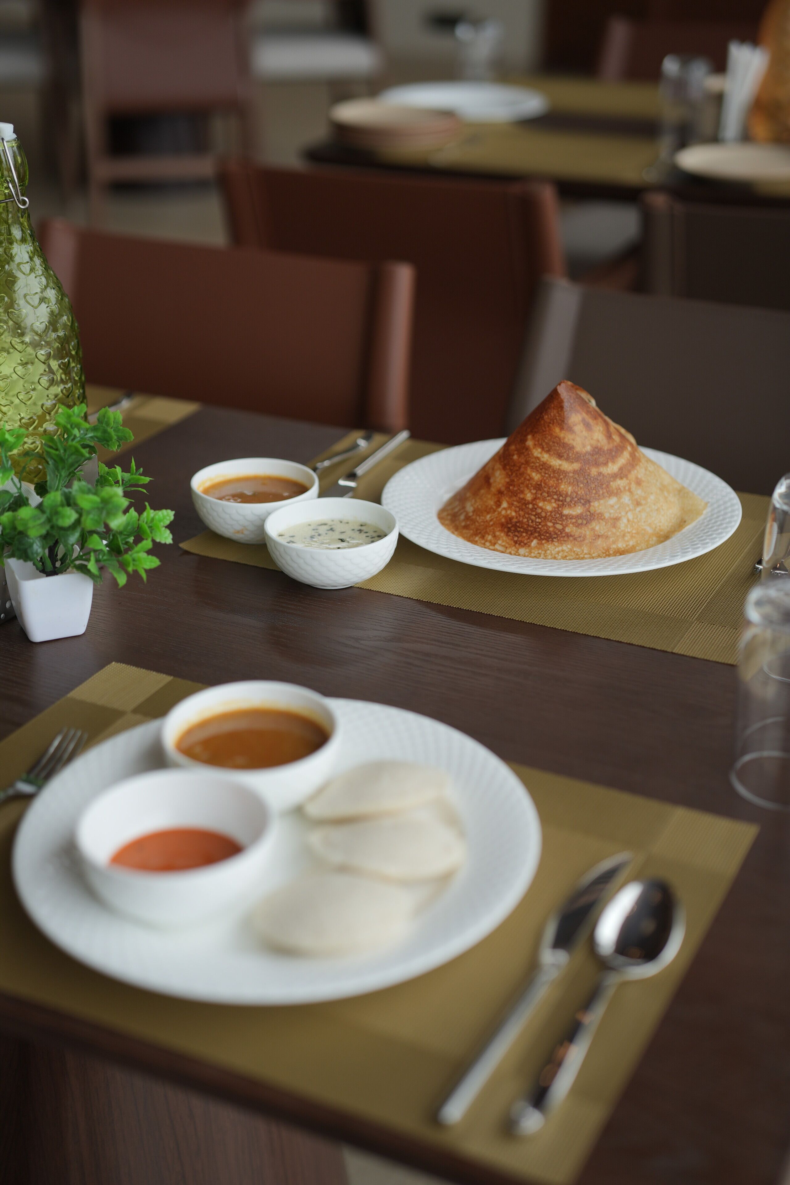 A dining table with a plate of food, including a cone-shaped item, and several small bowls of sauce.