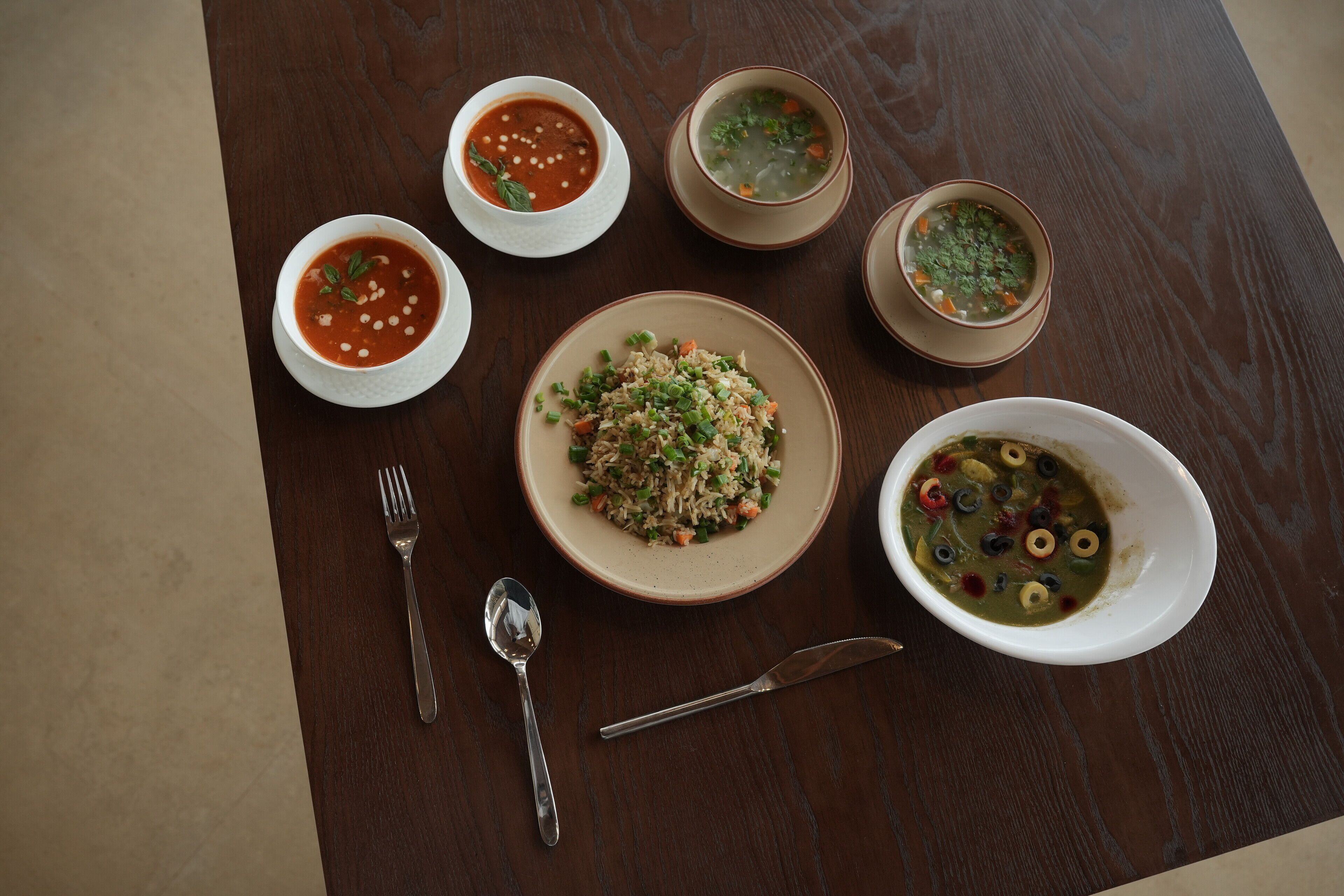 Une table où l’on trouve différents plats, notamment du riz, de la soupe et un bol d’olives.
