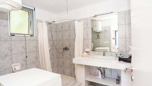 Une salle de bain avec une douche, un lavabo, des toilettes et une fenêtre.