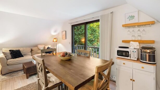 Una sala de estar acogedora con una mesa de comedor de madera, un sofá y una zona de cocina con microondas y tostadora.