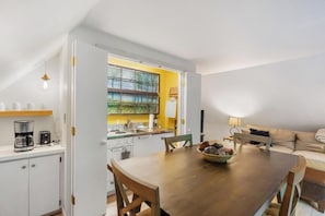 Eine kompakte Küche mit Essbereich, ein Fenster mit Blick und ein Sofa im Wohnbereich.