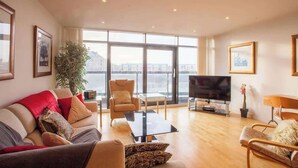 Un salon spacieux doté d’une grande fenêtre, d’un téléviseur à écran plat et d’un coin salon confortable.