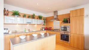 Une cuisine moderne avec des meubles en bois, un plan de travail en granit et des appareils électroménagers en acier inoxydable.