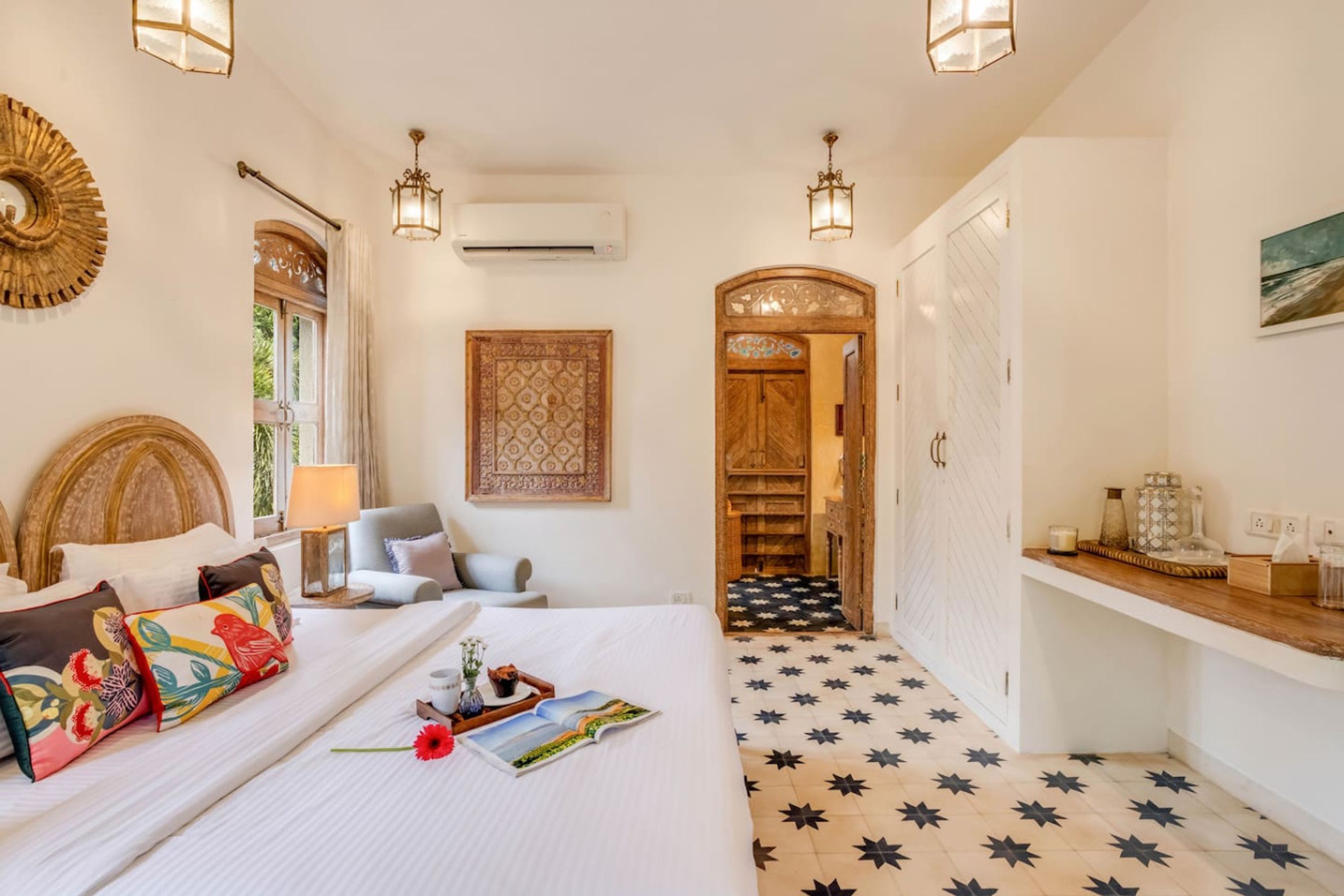 A hotel room with a large bed, a bedside table, a nightstand, a mirror, a wall-mounted air conditioner, and a star-patterned floor.