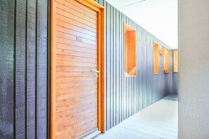 A corridor with a wooden door and windows, a concrete floor, and a grey wall. - Apartment Rental in La Plagne - Montchavin - Les Coches (Bellentre)