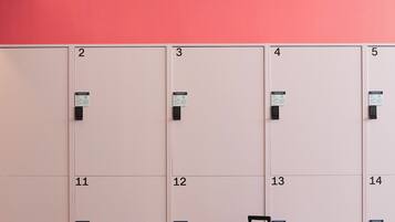 Een rij lockers genummerd van 2 tot 14 tegen een roze muur, met een koffer voor locker nummer 13.