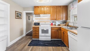 A kitchen with wooden cabinets, a white stove, a microwave, and a dishwasher. - Shannon A - downstairs (Ocean City)
