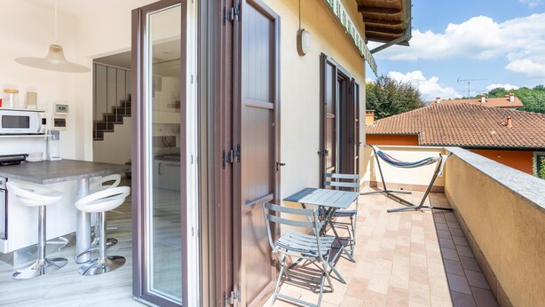 Cocina integrada con comedor, puertas de cristal correderas y un balcón con mobiliario exterior.
