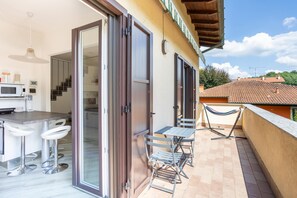 Cucina open space con zona pranzo, porte scorrevoli in vetro e un balcone con posti a sedere all'aperto.