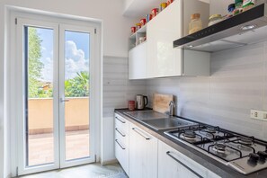 A modern kitchen with a gas stove, a sink, and a sliding glass door leading to an outdoor area. - Apartment 'Rocca Lake House' with Shared Garden, Balcony and Wi-Fi (Angera)
