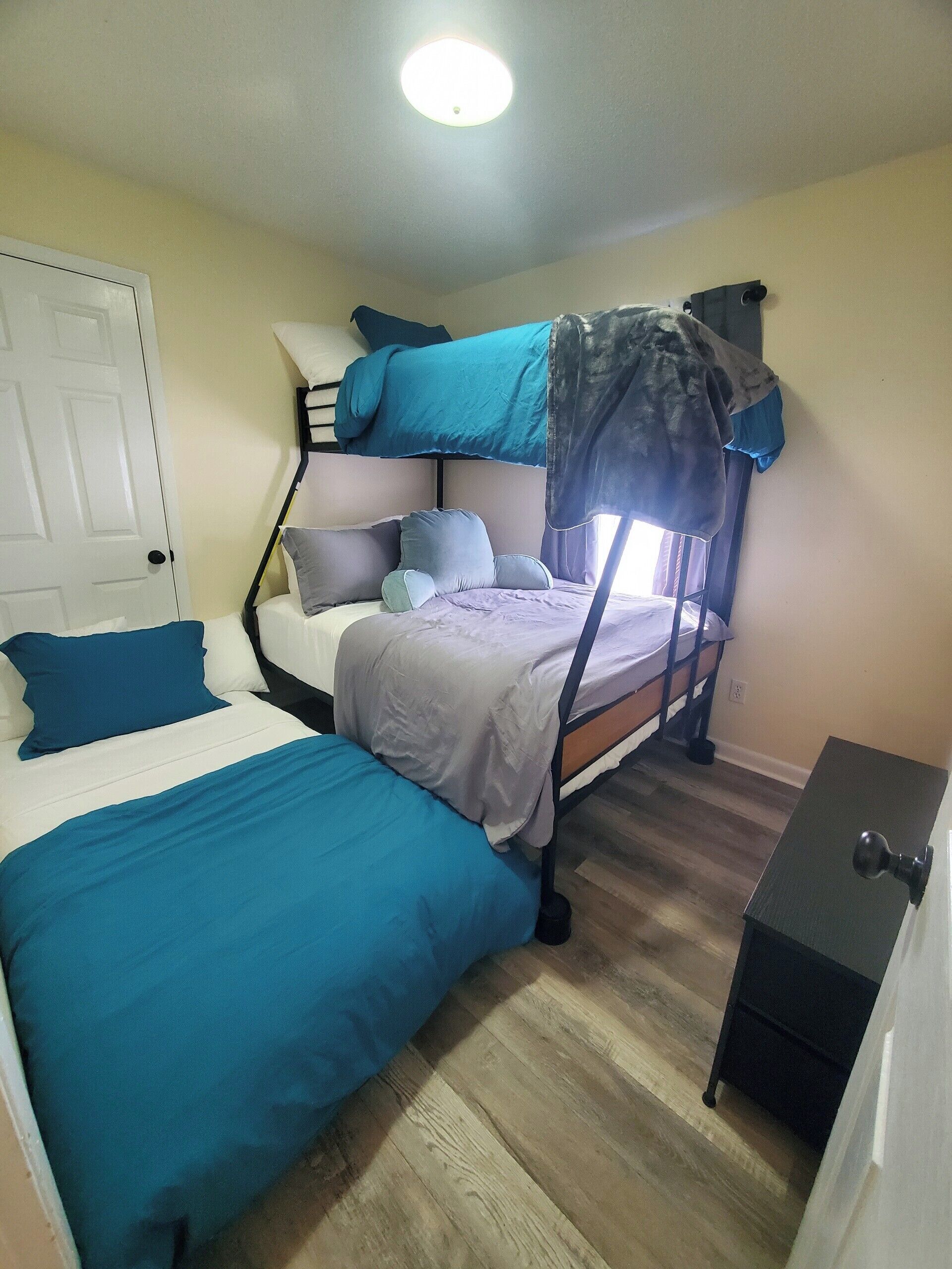 A dormitory room with bunk beds, a desk, and a door.