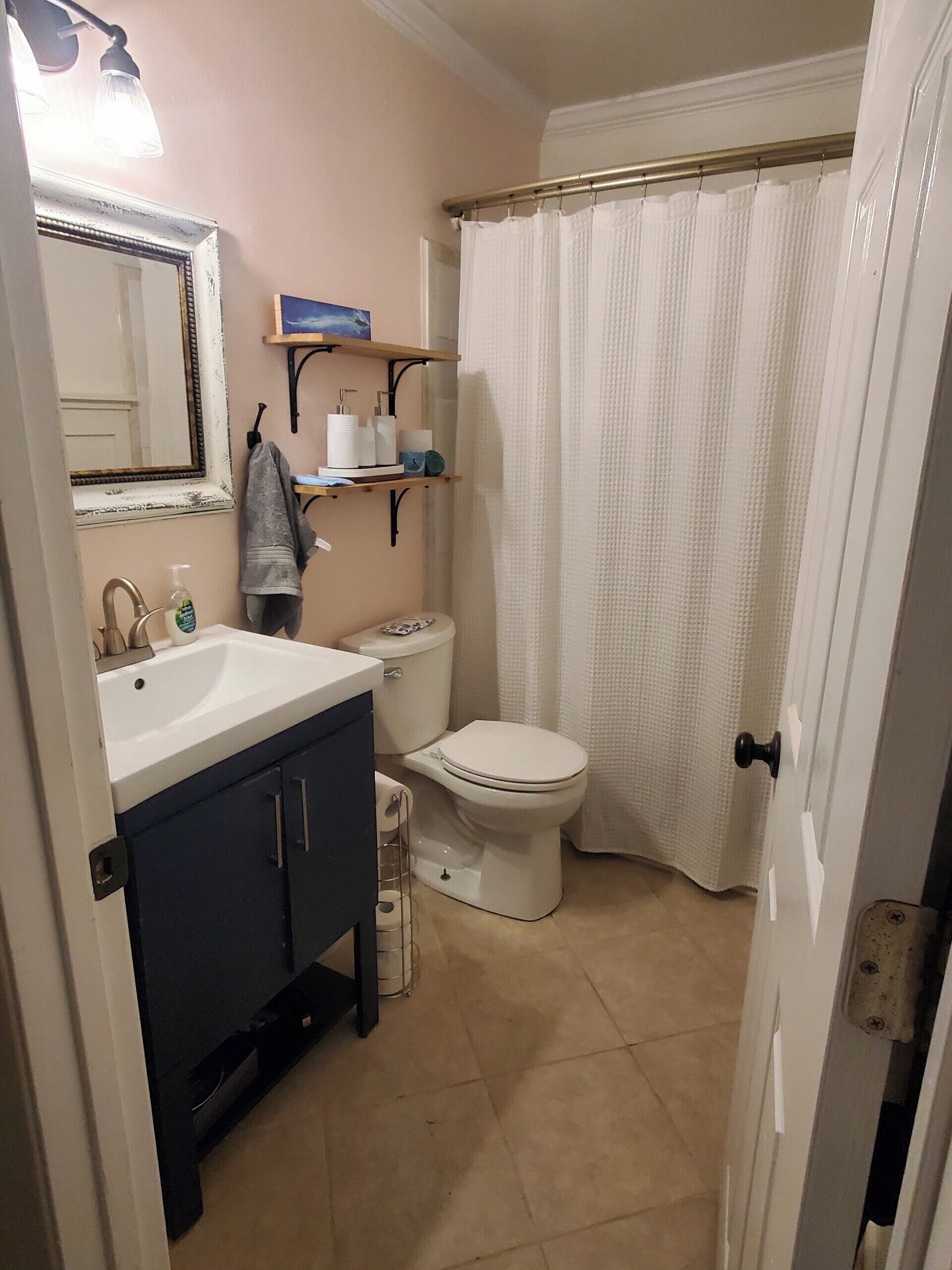 A bathroom with a sink, mirror, toilet, and shower curtain.