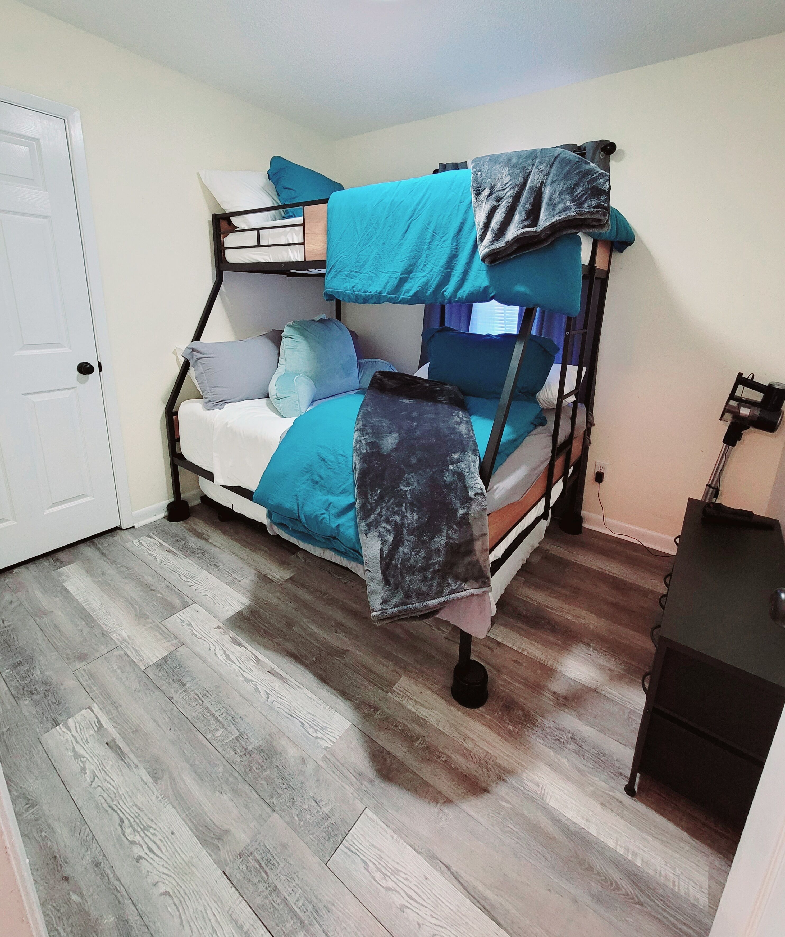 A bunk bed with blue bedding and a small desk with a lamp.