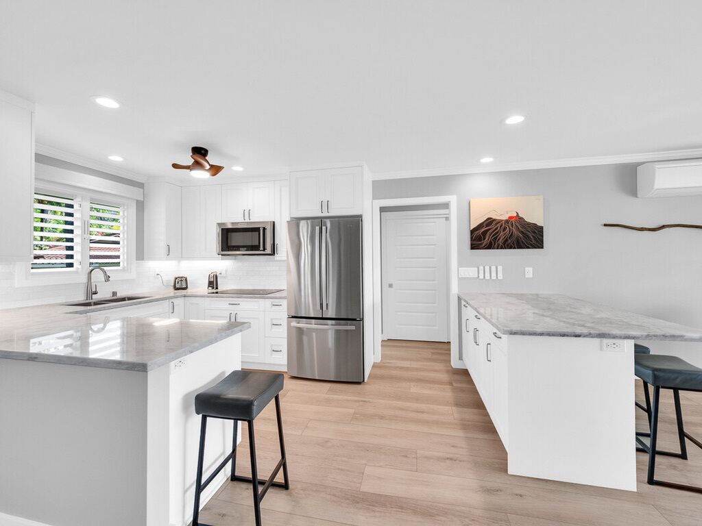 A modern kitchen with white cabinetry, stainless steel appliances, and a marble countertop island.