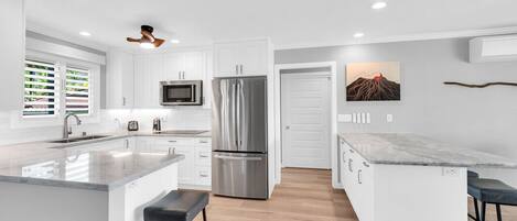 A modern kitchen with white cabinetry, stainless steel appliances, and a marble countertop island.