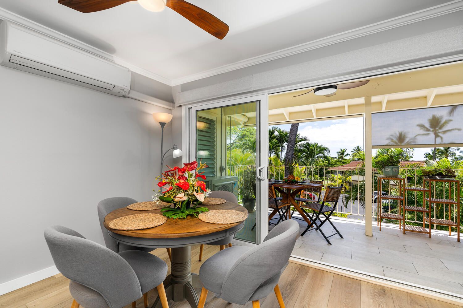 A dining area with a round table, grey chairs, and a floral centerpiece.