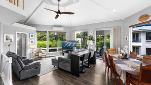 A spacious living area with a TV, seating, and a dining table.