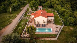 Una casa circondata da un giardino e da una strada, con piscina.