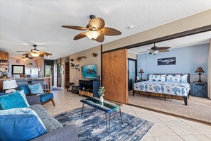A spacious living area with a sofa, coffee table, and a bed with a patterned bedspread. - Kona Bali Kai 307 Oceanfront– 2BR/2BA Condo with Panoramic Views (Kailua-Kona)