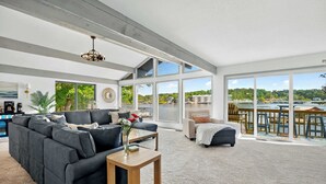 Un salon spacieux avec un grand canapé d’angle, une table basse et une vue sur le bord de l’eau.