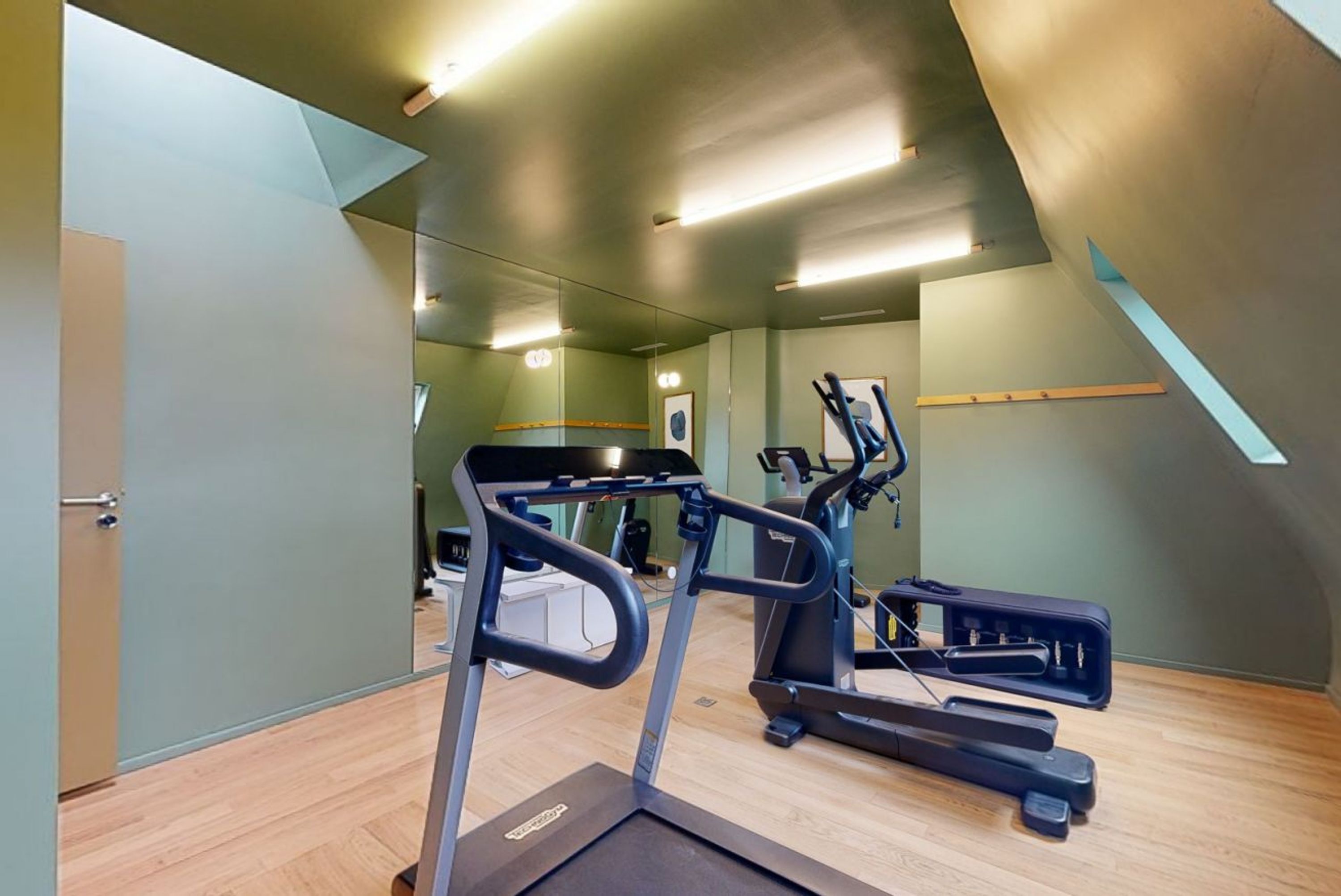A modern gym with a treadmill, elliptical, and stationary bike.