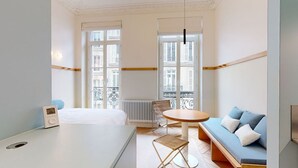 A hotel room with a bed, a round table, a sofa, and a radiator. - Altido Delightful 1bed Studio w Shared Co-working Space (Paris)
