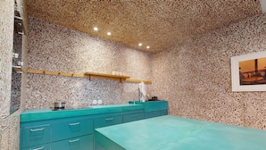 A kitchen with a speckled backsplash, teal cabinetry, and a wooden shelf above the sink. - Altido Delightful 1bed Studio w Shared Co-working Space (Paris)