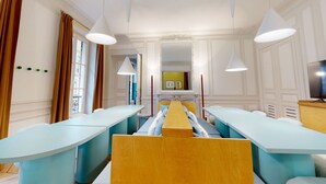 A hotel room with a long, light blue sofa bed, a wooden headboard, and a television on a wooden stand. - Altido Delightful 1bed Studio w Shared Co-working Space (Paris)
