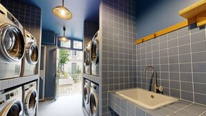 A laundry room with multiple washing machines, a sink, and a tiled backsplash. - Delightful 1-bed Studio w Shared Co-working Space (Paris)
