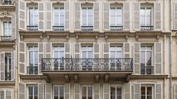 A multi-story building with white-framed windows and shutters, ornate balconies with wrought iron railings, and classical architectural details. - Delightful 1-bed Studio w Shared Co-working Space (Paris)