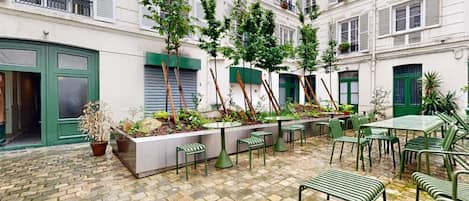 A courtyard with outdoor seating, potted plants, and a stone-tiled floor.