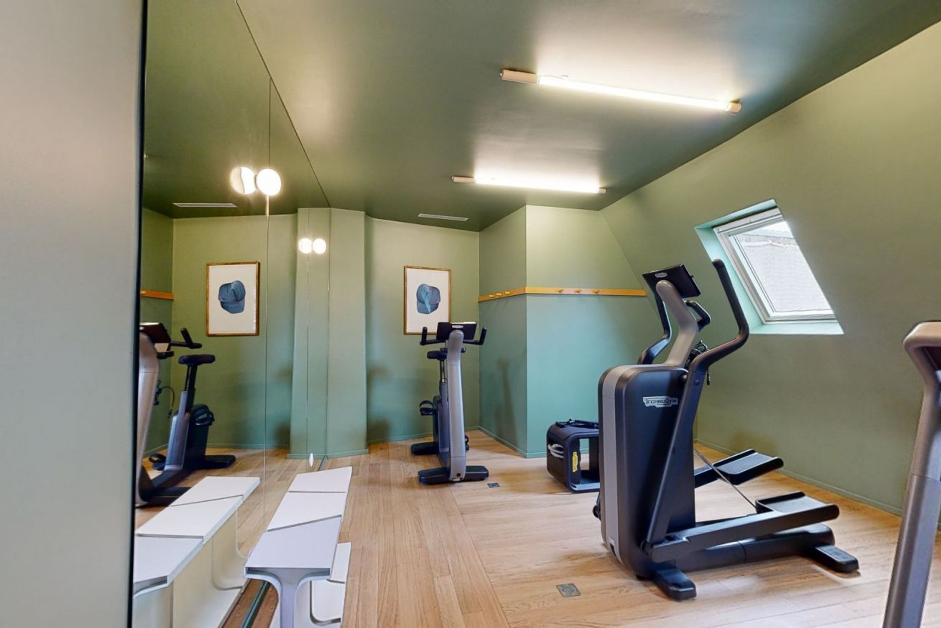 A gym with cardio machines, mirrors, and a window.