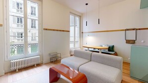 A modern living room with a sofa, a small table, and a radiator. - Altido Charming 2-bed Flat w Shared Spaces (Paris)