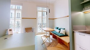 A modern living room with a dining table, a sofa, and a kitchen area. - Altido Delightful 1bed Studio w Shared Co-working Space (Paris)