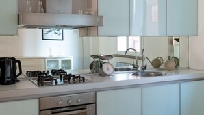 A modern kitchen with a gas stove, oven, sink, and a scale. - Beautiful Two-Level One-Bedroom Apartment – Mirable PM (Milan)