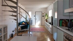 A modern kitchen with a built-in stove, a dining area with a white table, and a spiral staircase leading to an upper level. - Beautiful Two-Level One-Bedroom Apartment – Mirable PM (Milan)