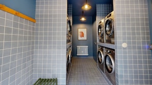 A laundry room with two washing machines, a radiator, and a framed picture on the wall. - Charming 2-bed Flat w Shared Spaces (Paris)
