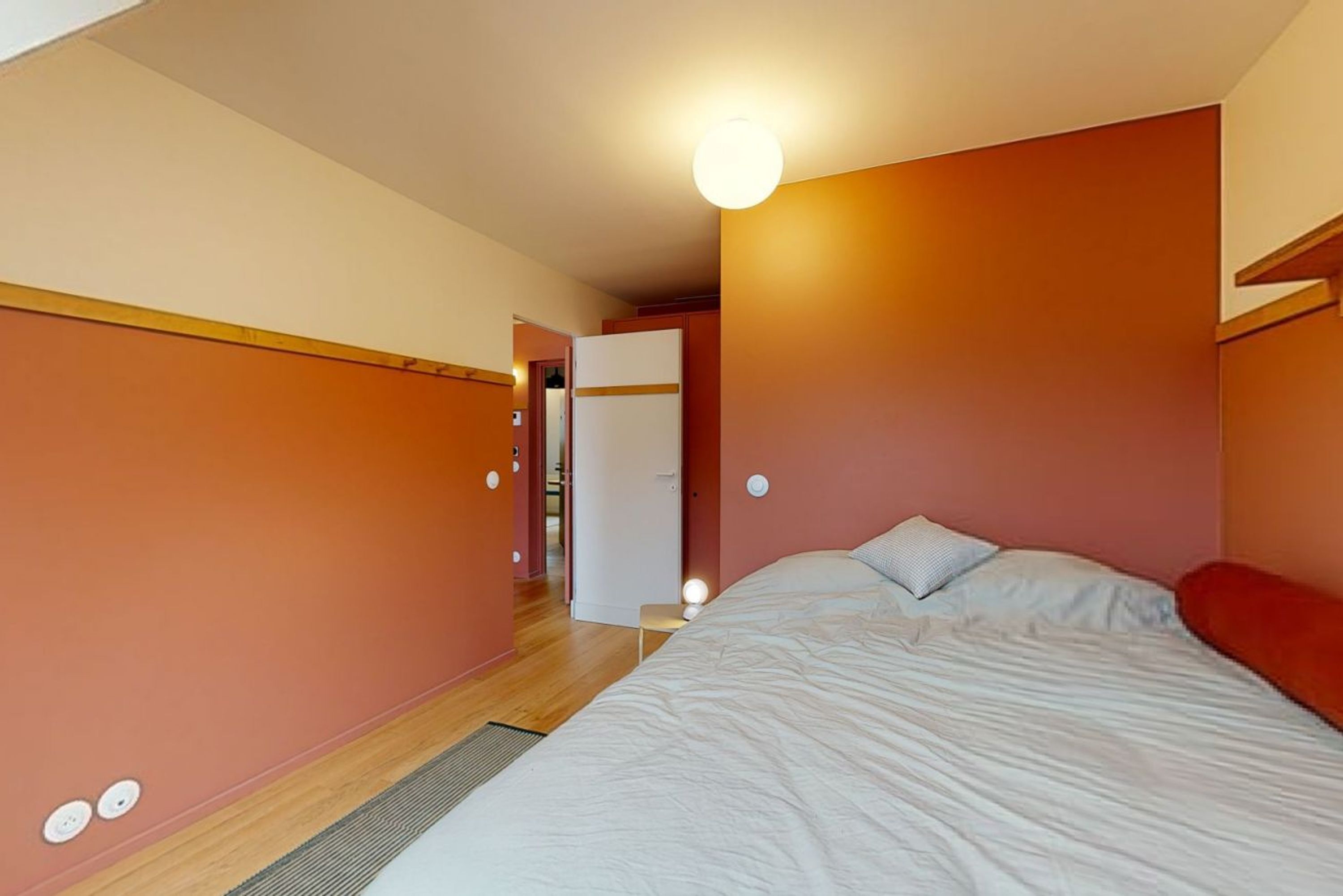 A bedroom with a bed, a door, and a light fixture.