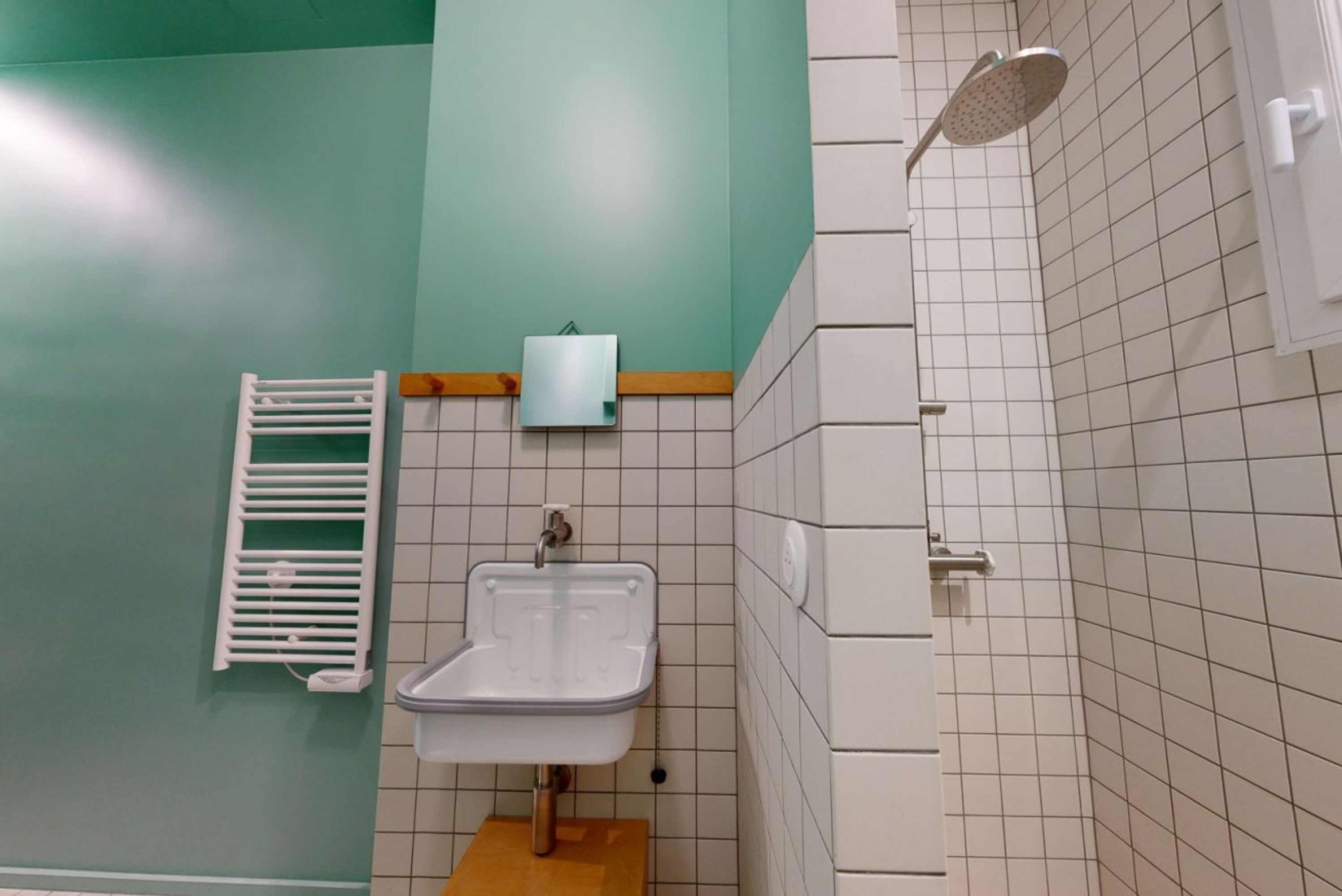 A bathroom with a sink, a towel rack, a shower, and a toilet paper holder.