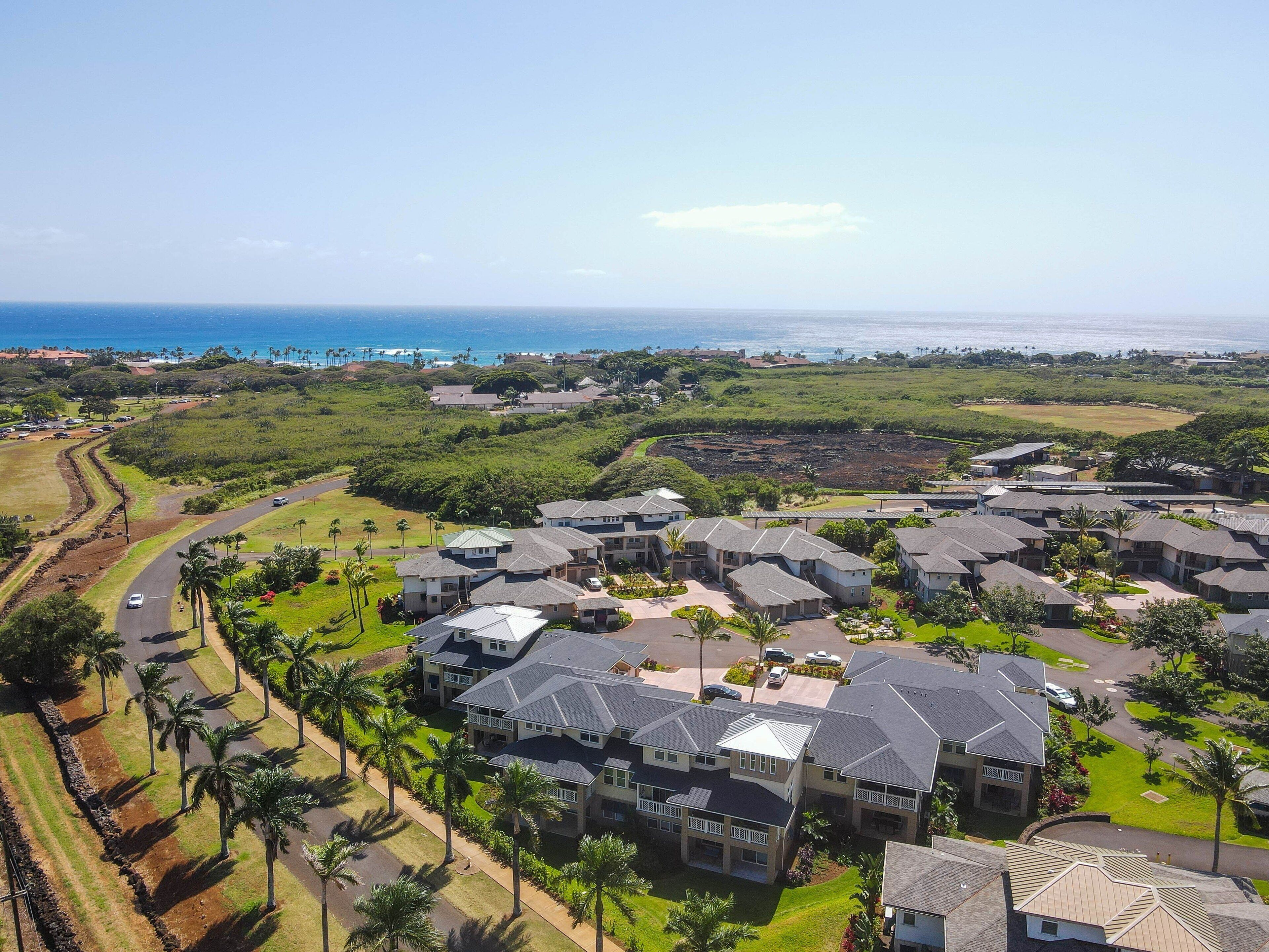 Área residencial com casas dispostas em círculo, rodeada por vegetação e vista para o oceano.