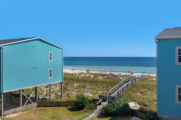 A coastal house with a wooden deck and a view of the beach.