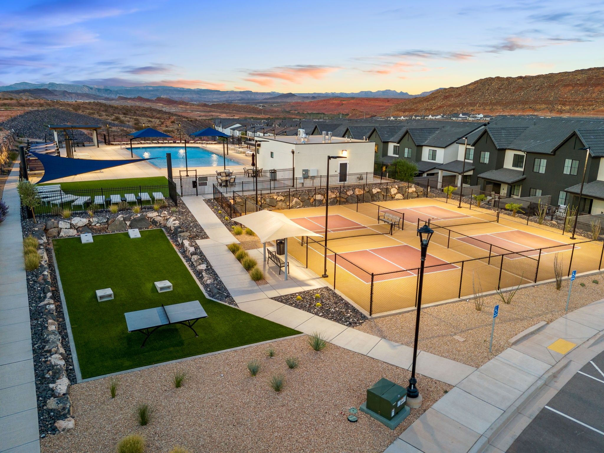 Zona residencial con piscina, canchas de tenis y casas con techos oscuros.