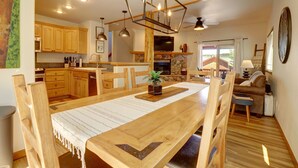 A spacious kitchen with wooden cabinets, a dining table, and a stone fireplace.