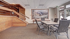 Une salle de conférence dotée d’une grande table, de quatre chaises, d’un escalier avec des rampes en bois et d’une grande fenêtre donnant sur les montagnes.