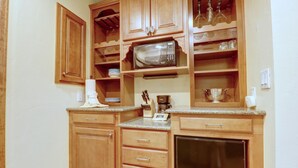 Une cuisine dotée de meubles de rangement en bois, d’un four à micro-ondes, d’un réfrigérateur et d’un plan de travail sur lequel sont disposés divers ustensiles de cuisine.