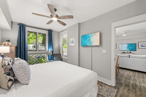 Un dormitorio con cama, ventilador de techo, televisor y vistas al exterior.
