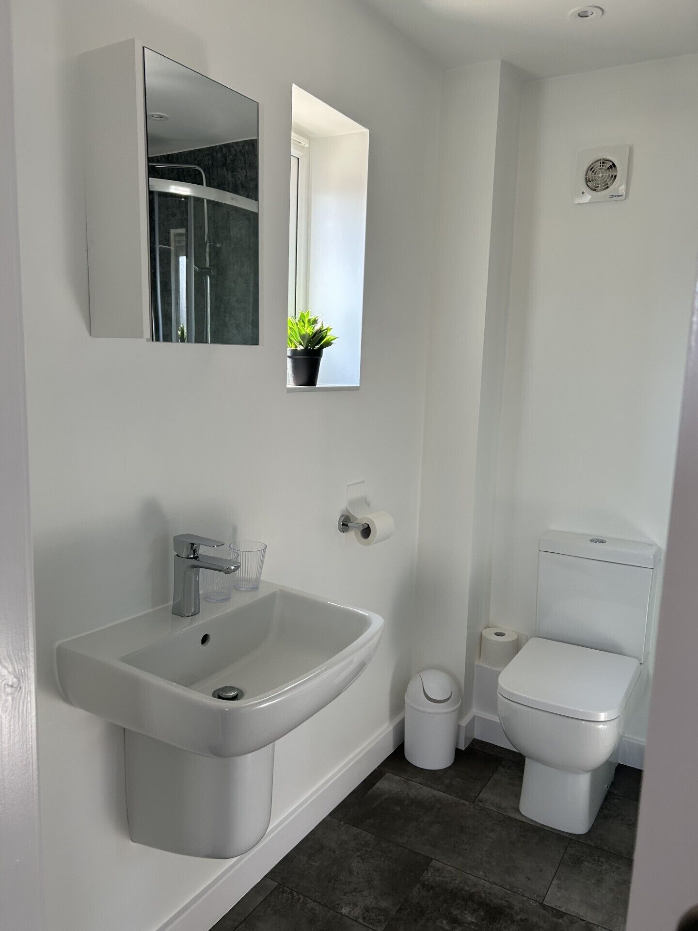 Un bagno moderno con lavandino, specchio e water bianchi.