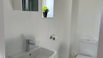 Un bagno moderno con lavandino, specchio e water bianchi.